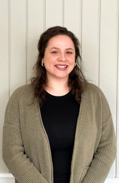 A smiling woman wearing a green cardigan and black top.