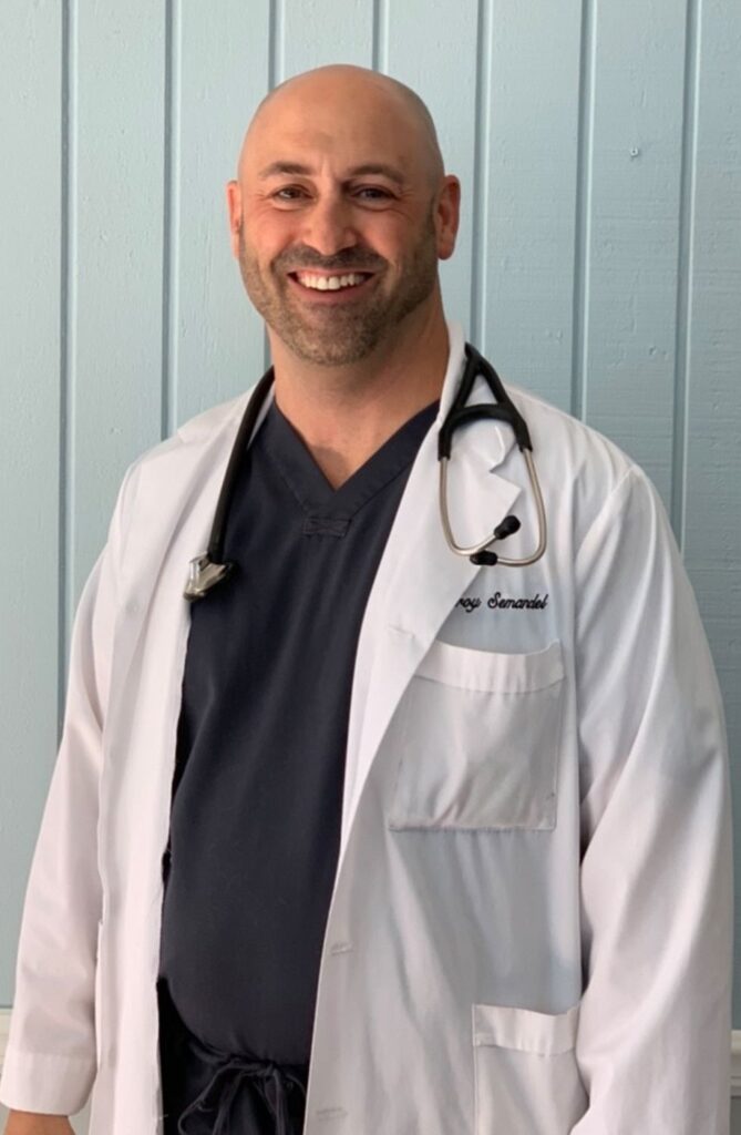 Bald male doctor smiling, wearing a lab coat and a stethoscope.