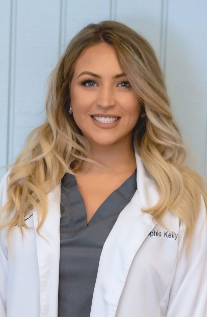 Portrait of a smiling woman in a white lab coat and gray top.