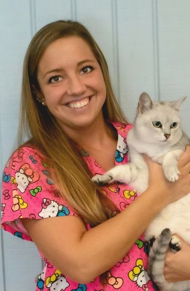 Woman in patterned scrubs holding a white and gray cat.